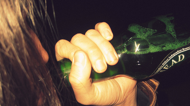נערה שותה מבקבוק בירה ירוק